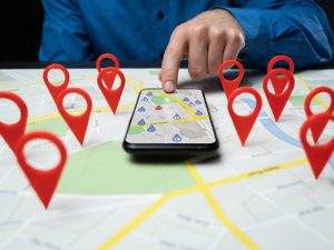 Hand pointing at a smartphone map with red location markers, representing business directories Australia for local listings.