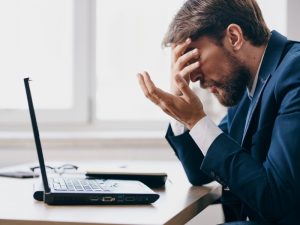 Frustrated man looking at his laptop, highlighting signs your website needs SEO packages for better performance.