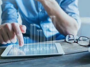 A businessman analysing a digital bar graph on a tablet, representing digital marketing cost trends and financial insights.