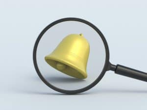 Magnifying glass focused on a yellow notification bell, symbolizing exploration of how to set up Google Alerts effectively.