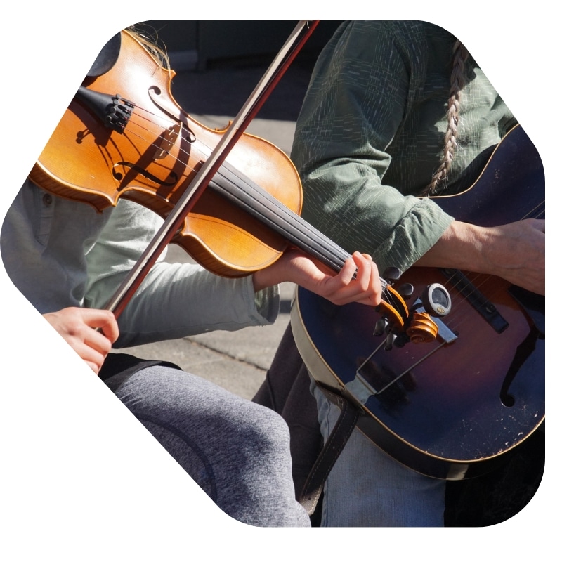 Marketing for Musicians – Street performers playing violin and guitar, engaging audience with live music in an outdoor setting.