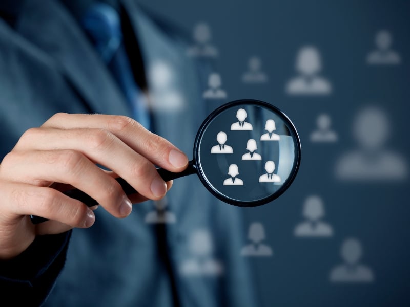 Businessperson using magnifying glass to analyse target audience while working with a digital marketing agency