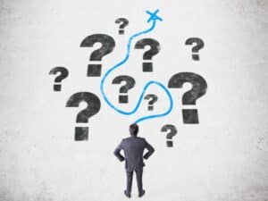 Businessperson facing multiple question marks with a blue line showing direction, symbolising digital marketing advertising strategy planning.