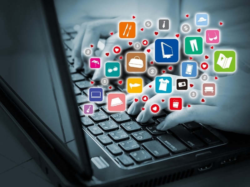 Hands typing on laptop with colourful icons representing engagement when working with a digital marketing agency