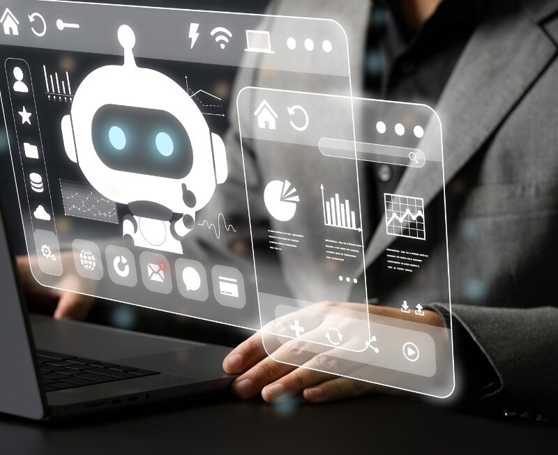 A person in a suit sits at a desk, with hands resting, beside a holographic interface displaying an AI Automation chatbot, data charts, and various icons.