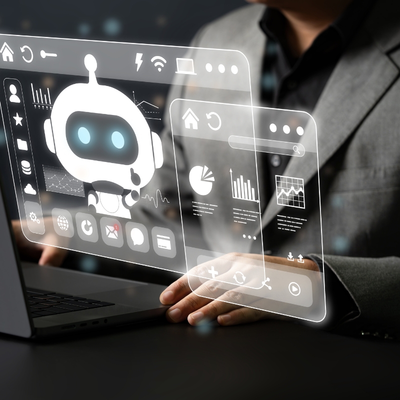 A person in a suit sits at a desk, with hands resting, beside a holographic interface displaying an AI Automation chatbot, data charts, and various icons.